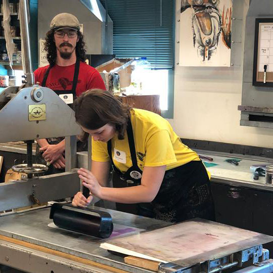 Student Jessica Hedlun and staff member Sam Speir working on a print