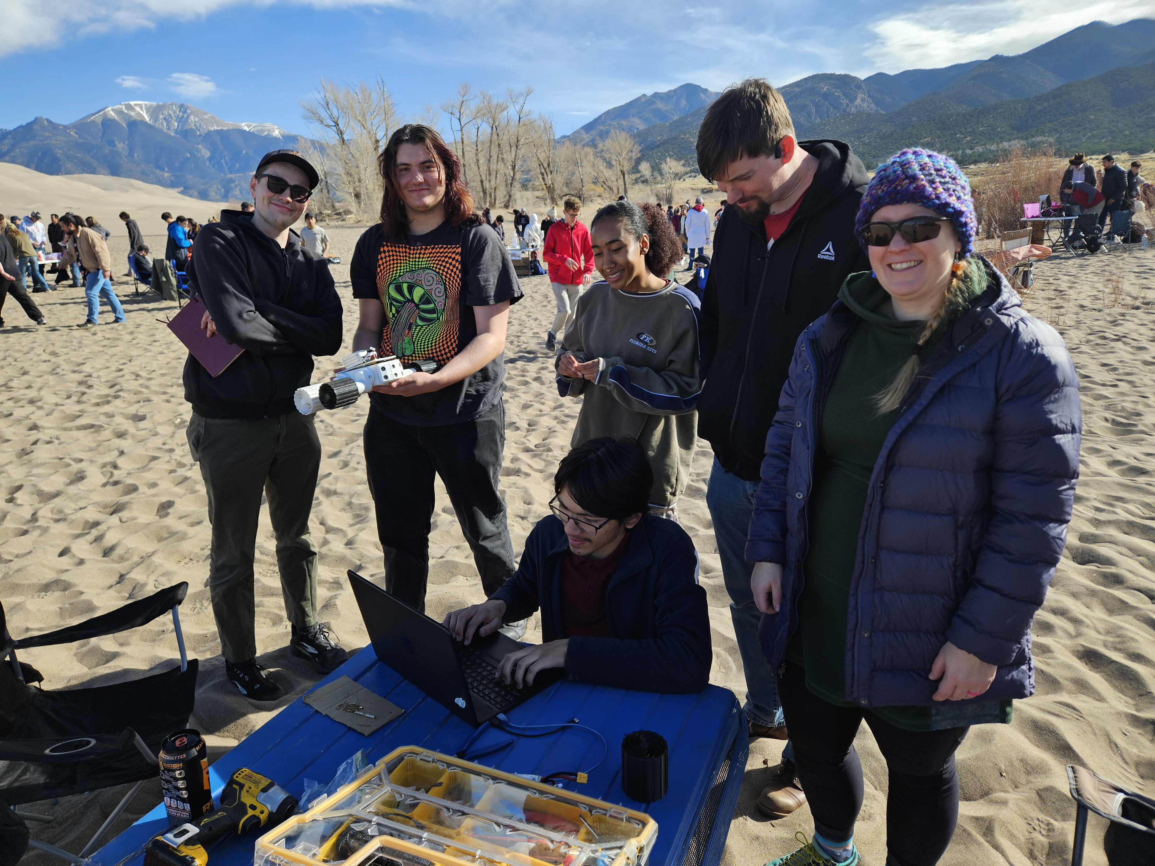 IEEE team at the robotics challenge standing on sand with their robot