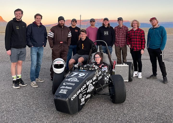 team members standing behind their FSAE race car