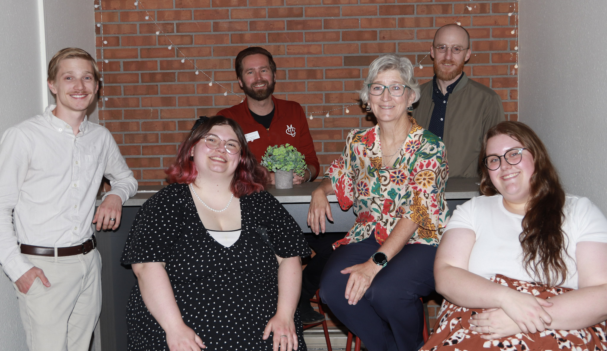 people on team gold posing for photo in space with brick walls