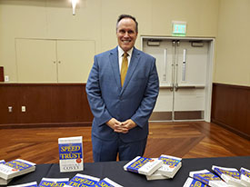 Stephen Covey standing by his book