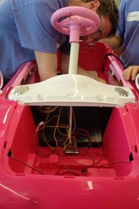 Student rewiring a child's pink car