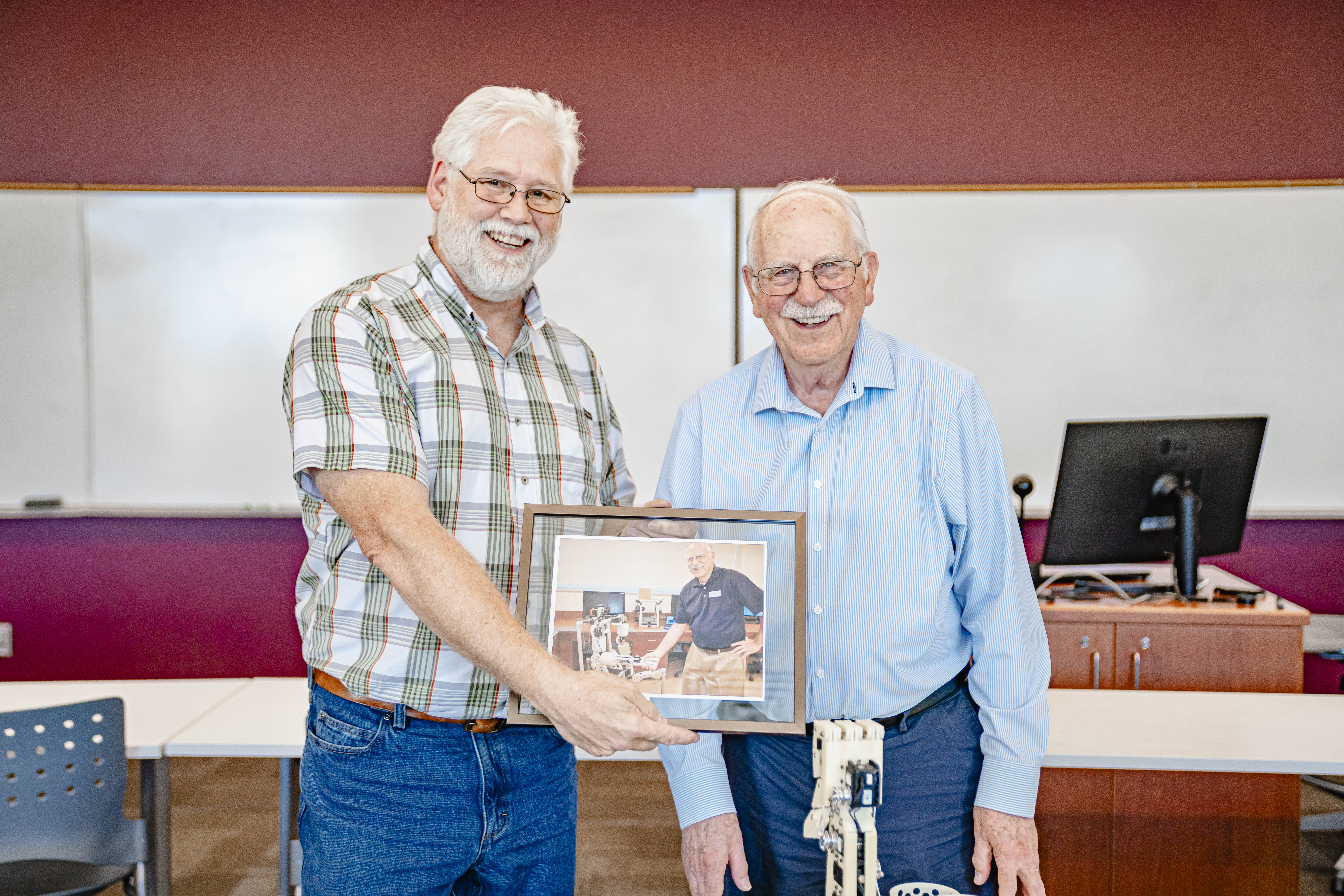 Associate Professor of Computer Science Karl Castleton and Chuck Hull hold a framed photo from Hull’s previous campus visit